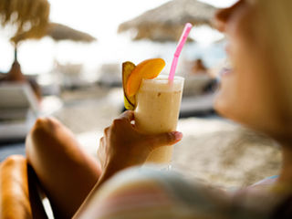 woman holding a drink on a beach